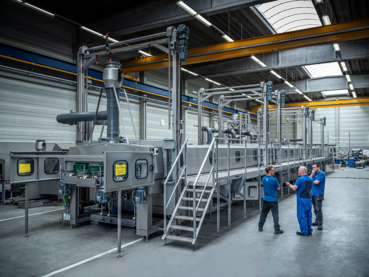 James is in gesprek met twee collega's in de fabriekshal van Numafa